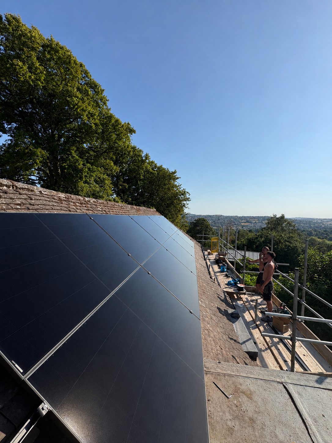 Cube Solar installing a flush solar array on a stone-tiled roof, panels sitting level with the stone coursing